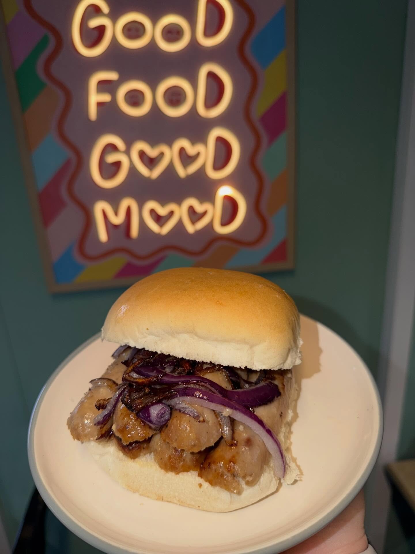 Sausage barm with caramelised red onions in front of the Good Food Good Mood sign at The Oven Door Cafe
